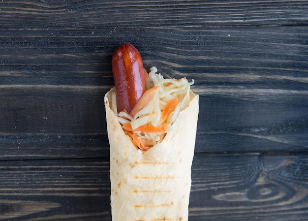 Sausage and lettuce wrapped in pita bread on wooden backgroundphoto with copy space
