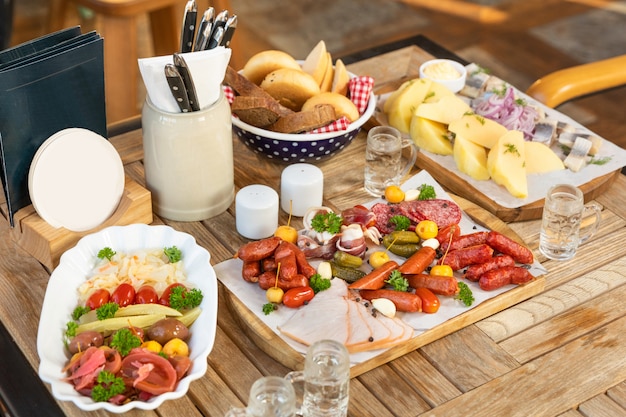 Sausage with cheese and fermented cucumbers, snacks with vodka on the table