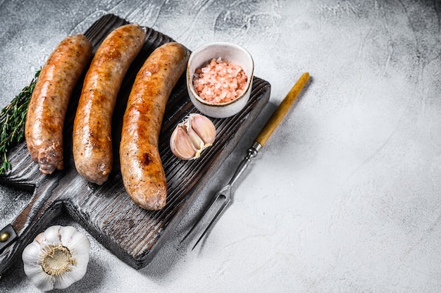 Sausages barbecue fried with spices and herbs on a wooden cutting board