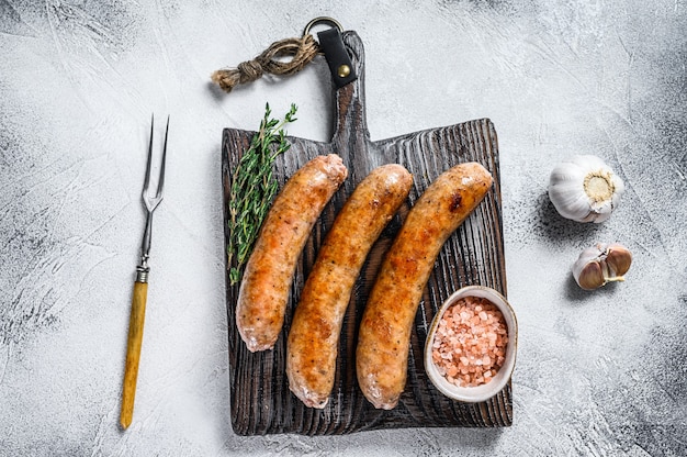 Barbecue di salsicce fritte con spezie ed erbe aromatiche su un tagliere di legno