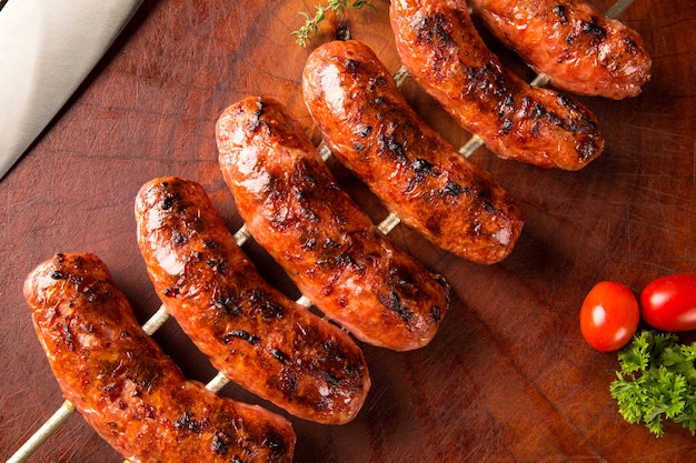 Sausages on the barbecue spit on wooden space