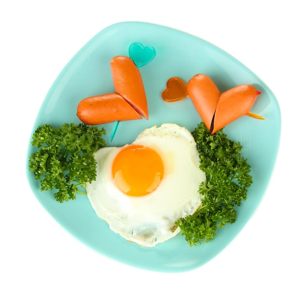 Sausages in form of hearts, scrambled eggs and parsley, on color plate, isolated on white