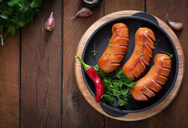 Sausages on the grill pan on the wooden table