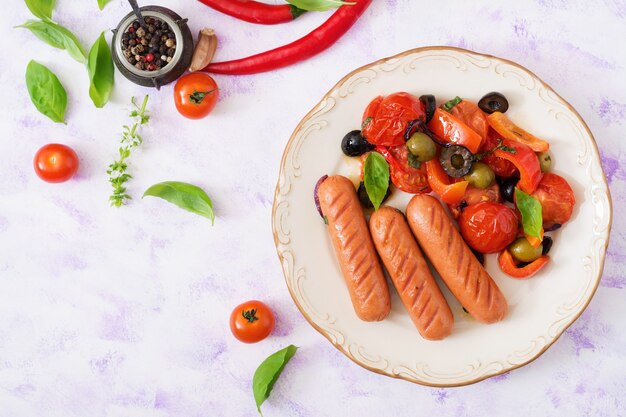 Sausages grilled with vegetables in the Greek style on plate.