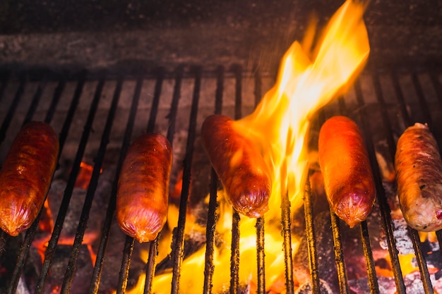 Foto salsicce che grigliano i carboni ardenti incandescenti in un barbecue portatile