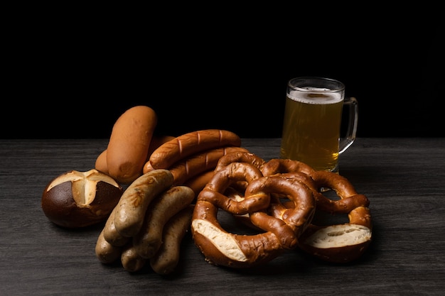 sausages oktoberfest pretzels and beer with dark background and wood table