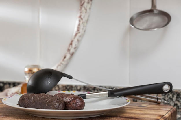 Sausages on a plate next to a saucepan a fire bar hung on the wall