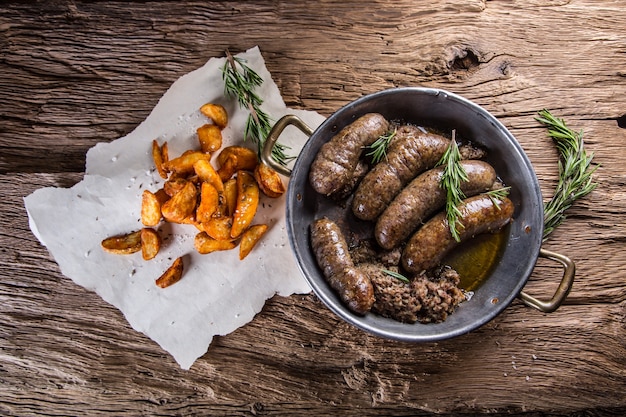 Sausages.Roasted pork sausage in a pan with potatoes and rosemary.