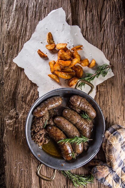 Foto salsicce.salsiccia di maiale arrosto in padella con patate e rosmarino.