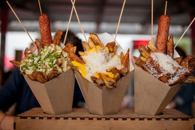 Sausages with grated cheese and french fries in a cardboard envelope street food festival snack