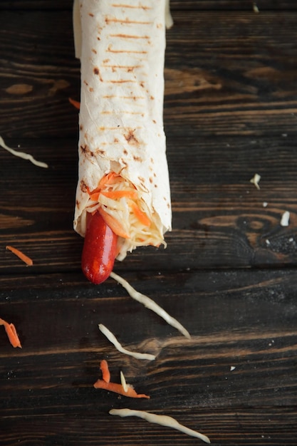 Sausages with salad in pita bread on wooden backgroundphoto with copy space