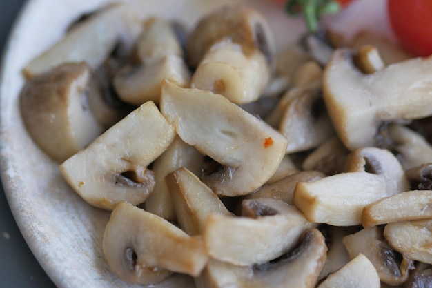 Sauteed mushrooms with garlic and parsley on a black plate on white background