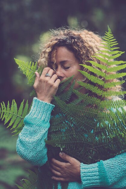 Save the earth planet and celebrate earths day with adult woman hug and hold a green leaf in the forest wood enjoying nature stop deforestation concept with people love nature