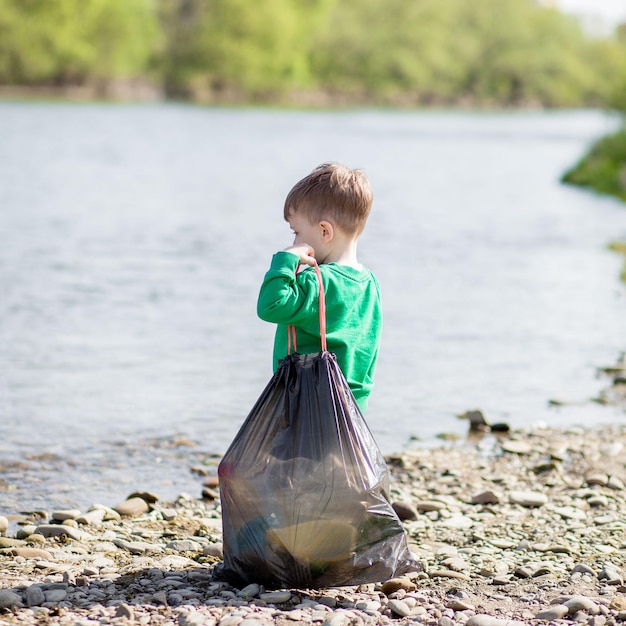 Save environment concept a little boy collecting garbage and plastic bottles on the beach to dumped into the trash