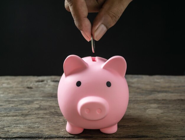 Save money and account banking for finance concept Hand with coin on piggy bank blurred background
