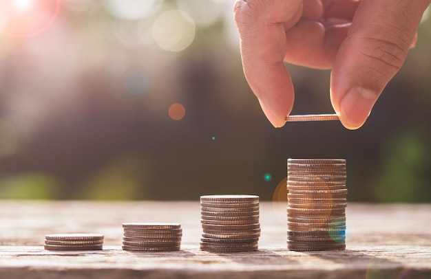 Save money and business finance concept. male hand stacking
coins money growing in morning sunlight