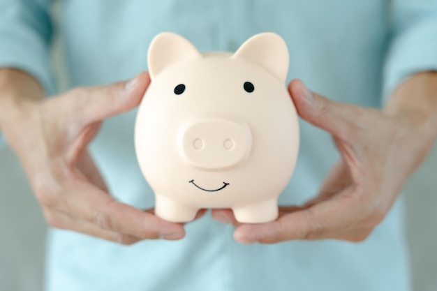 돈을 절약하기 위해 돈을 저축하는 비즈니스 우먼은 돈을 절약하기 위해 돼지 저금통에 동전을 넣습니다. 금융 사업 투자 은퇴 미래 회계 계획 생활은 은행 가족 건강을 절약합니다.