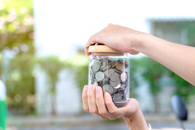 Foto risparmia il concetto dei soldi con le monete della tenuta della mano in bottiglia
