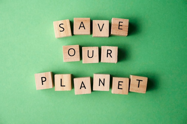 Photo save our planet words message written on wooden blocks over green background top view save planet climate changes concept