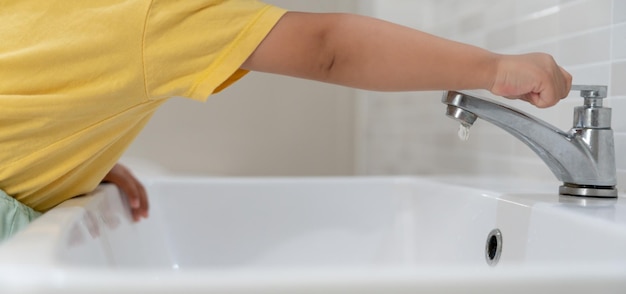 Save water Little kid keeps turning off the running water in the bathroom to protect environment Greening planet reduce global warming Save world life future risk energy crisis water day