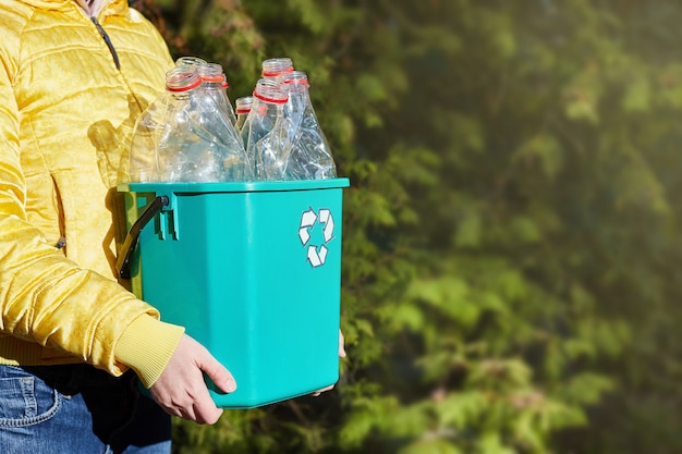 Save the world plastic free. girl\'s hands hold a box with empty\
plastic bottles. sustainability ecology environmental\
conservation.