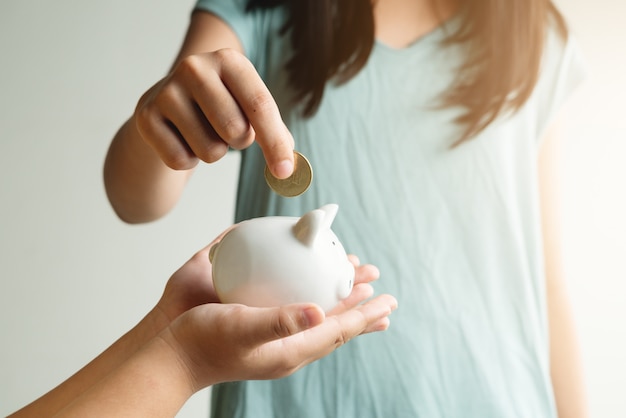 Saving and business concept, two little girl with piggy bank and coins at home