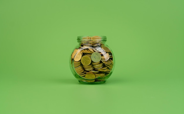 Saving coins in a glass jar Finance and financial investment coin bank salary wages cash flow