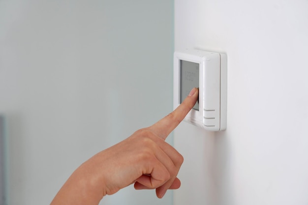 Saving energy concept human hand turning down temperature on digital display