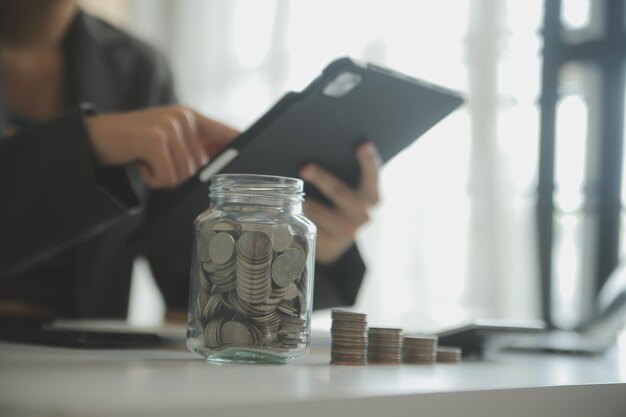 saving money and accounting concept business man putting coin insert to jar and make acounting book for finance management to investment and saving