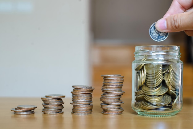 Saving money concept female hand putting money coin stack for\
the future growing business education and retirement she felt that\
saving money made his life safe