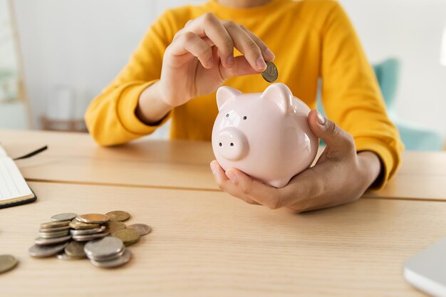 Saving money investment for future African american girl holding pink piggy bank and putting money coin Saving investment budget business wealth retirement financial money banking concept