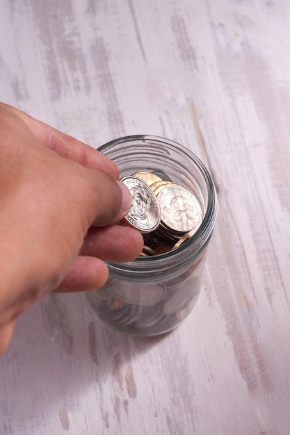 savings of coins deposited in a glass jar (dollar), on a wooden base. Investment and savings concept