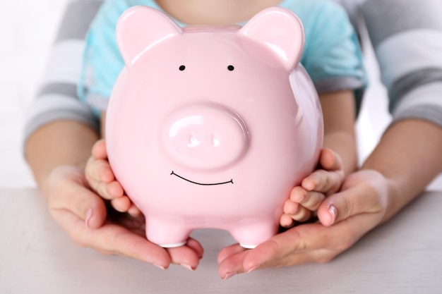 Savings concept Hands holding piggy bank close up