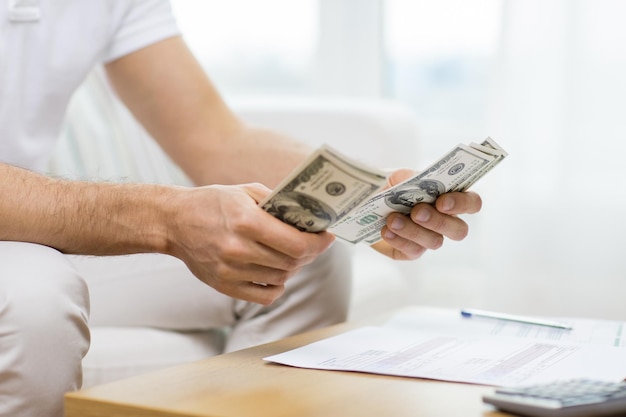 savings, finances, economy and home concept - close up of man hands counting money at home