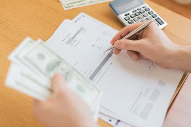 Photo savings, finances, economy and home concept - close up of man with calculator counting money and making notes at home