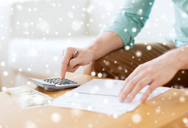 savings, finances, paperwork and people concept - close up of man with calculator counting money and making notes at home