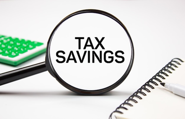 SAVINGS TAXES text through a magnifying glass next to a calculator Financial business concept