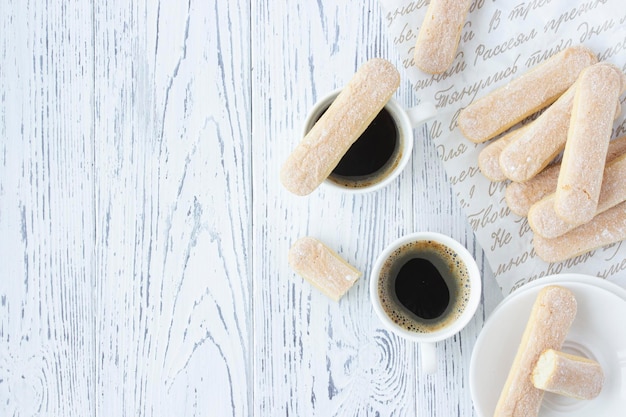 Savoiardi-koekjes bakken voor tiramisu-dessert met koffie op een witte houten achtergrond