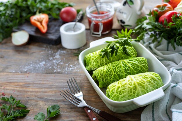 Savooikoolrolletjes gevuld met vlees, rijst en groenten op een rustieke tafel.