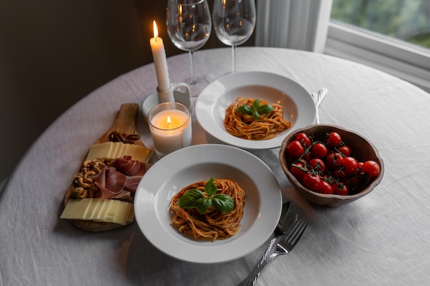 Photo savory bolognese pasta with basil prosciutto cheese and nuts a table set with herry tomatoes