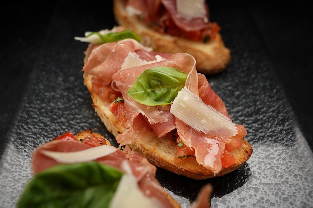 Savory Bruschetta with Salmon Ham and Parmesan Cheese on Dark Background