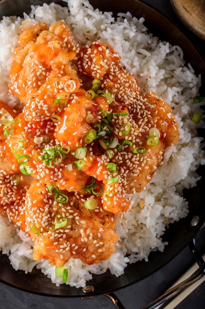 Savory Delights CloseUp of DeepFried Orange Chicken Served on a Bed of Steamed White Rice in 4k