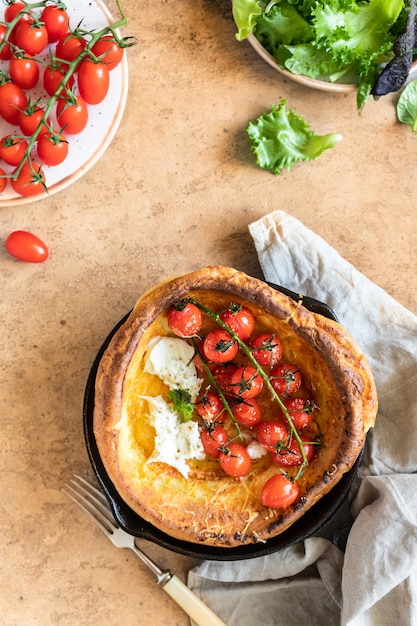 Pancake olandese salato con pomodori arrosto, mozzarella e foglie di insalata cucina danese