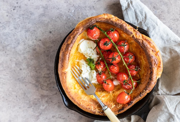 Savory Dutch baby pancake with roasted tomatoes mozzarella and salad leaves Danish cuisine