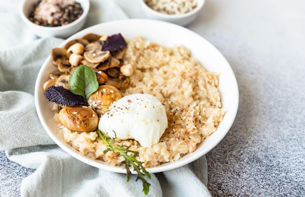 Porridge salato fiocchi d'avena o di farro con uova in camicia, funghi ed erbe aromatiche cibo sano dieta keto