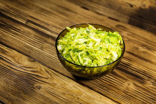 Салат из савойской капусты в стеклянной миске на деревянном столе