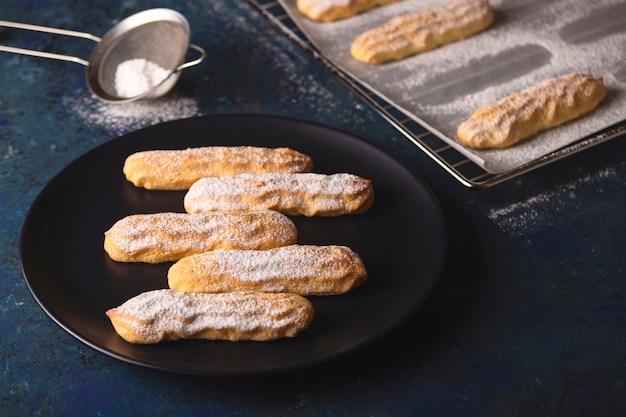 Foto savoyardi koekjes bestrooid met poedersuiker op blauw