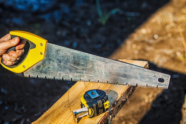 Saw with a construction tape measure on wooden board. Wooden plank