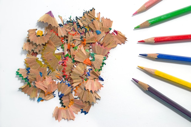 Sawdust of several colored pencils on white background