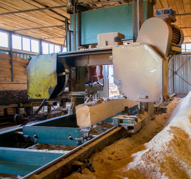 Sawmill. Process of machining logs in equipment sawmill machine saw saws the tree trunk on the plank boards. Wood sawdust work sawing timber wood wooden woodworking